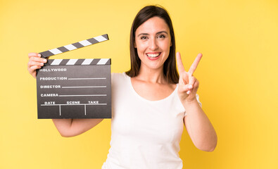 young adult pretty woman smiling and looking friendly, showing number two. cinema clapper concept
