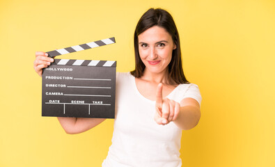 young adult pretty woman smiling proudly and confidently making number one. cinema clapper concept