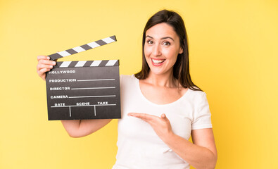 young adult pretty woman smiling cheerfully, feeling happy and showing a concept. cinema clapper...