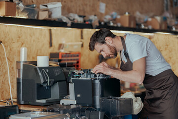 Man worker repair a coffee machine in own workshop