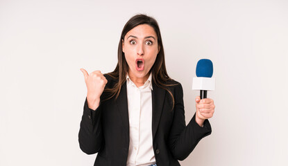 young adult pretty woman looking astonished in disbelief. presenter with a microphone concept