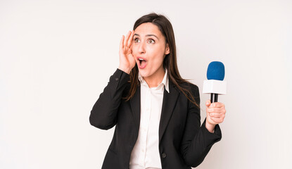 young adult pretty woman feeling happy, excited and surprised. presenter with a microphone concept
