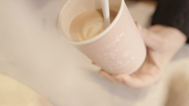 Barista doing a latte art on a take away coffee nicely. pouring milk in a cup of coffee slow-motion MXF.