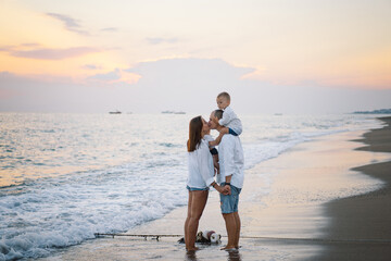 Happy family having fun playing beach in summer vacation on the beach. Happy family and vacations concept. Seascape at sunset with beautiful sky. Family on the beach.