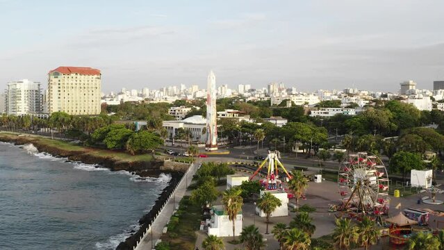 Obelisk in Juan Baron Plaza and amusement park along Malecon, Santo Domingo in Dominican Republic. Aerial forward