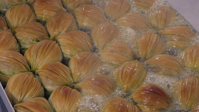 Turkish midye baklava with green pistachio nuts pouring sweet syrup