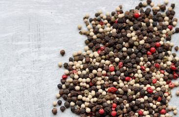 Peppercorns on a table. Light grey background with copy space. Colorful photo of spices. 