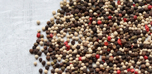 Peppercorns on a table. Light grey background with copy space. Colorful photo of spices. 