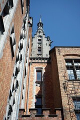 Schöne sanierte alte Fassaden aus rotbraunem Backstein und alter Turm vor blauem Himmel im...