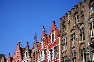 Belles façades anciennes colorées rénovées avec pignons à gradins et remparts de château contre un ciel bleu au soleil dans les ruelles de la vieille ville de Bruges en Flandre occidentale en Belgique