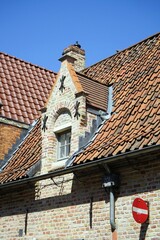 Kunstvoller alter Giebel an der Mansarde oder Dachgaube eines Wohnhaus mit rotbraunem Ziegeldach...