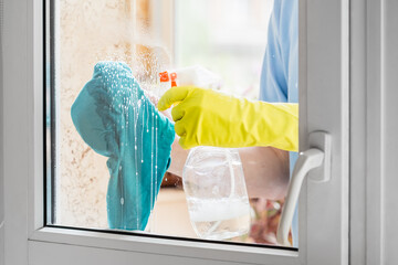 Man cleaning window with the detergent and rag
