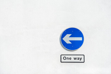 one way traffic sign on a white concrete wall
