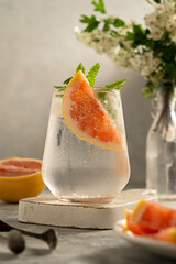 Refreshing, detox water summer drink with grapefruit, blooming brunch on background. Healthy...