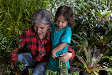Gardening with children. Grandmother teaches her Latin American grandson to work in her home garden. Hobbies and leisure, lifestyle, family life.