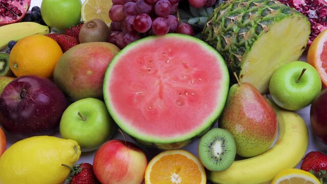 Assorted fresh fruits for healthy eating. Watermelon, pineapple, apple, pear, strawberry, kiwi, lemon, orange, grape, blueberry, pomegranate, mango, banana. Dolly shot 4k