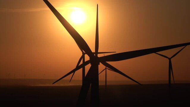 4k video with the silhouettes of a lot of wind turbines used to produce green eco energy. Electricity power industry. Sunset sky.