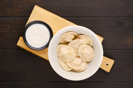 Traditional pelmeni with pork farce served with sour cream, view from above