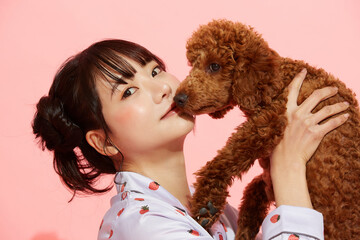 ペットと触れ合う若い女性のピンク背景のポートレート