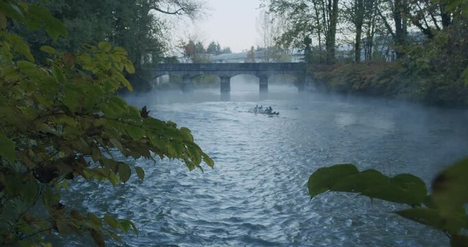 The Lambro river in the Park of Monza in Italy flows under an ancient bridge during a cold and foggy morning in autumn during the blue hour just before the sunrise