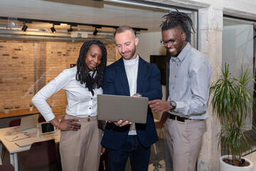 Group of multiethnic entrepreneurs using a digital tablet together in front of an office in a coworking space