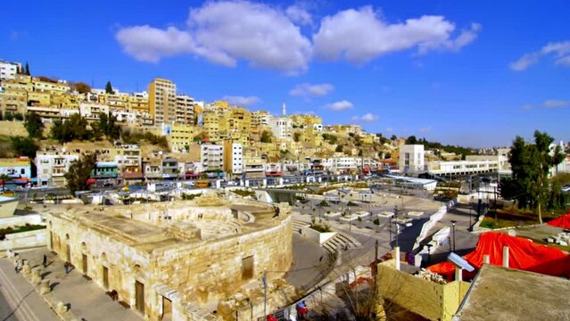 wide angle pan image of a coliseum or theater of Romanian or Greek origin  with his magnificence and the capacity against the background of the modern city in Amman Jordan on a sunny blue skies day