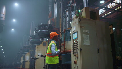 Engineer looking modern machine at huge industrial professional facility.