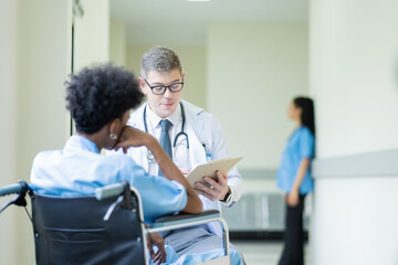 Obraz premium A male doctor in a medical uniform is discussing something with a patient in the hospital., Medicine and healthcare concept.
