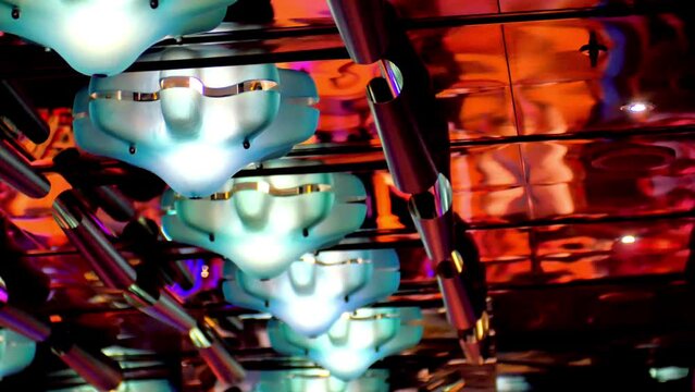 abstract image where you can see the ceiling of a nightclub on a cruise ship with focus blur and we see the lights and people dancing out of focus on the image the reflection of the ceiling glass