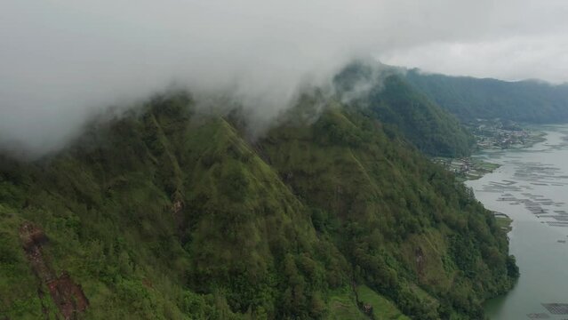 Clouds hanging above Trunyan hill at Lake Batur in Bali, natural volcanic landscape, aerial