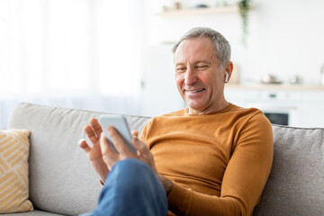 Happy mature man using cellphone wearing headphones