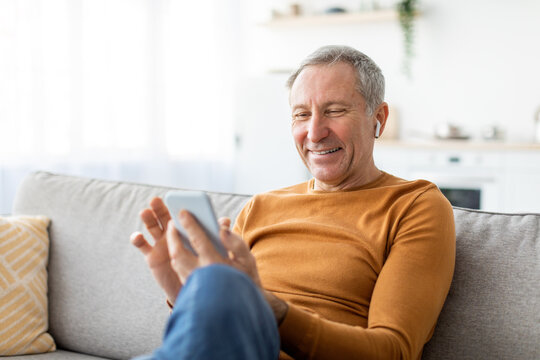 Happy mature man using cellphone wearing headphones - Powered by Adobe