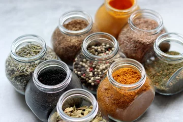 Foto op Plexiglas Different types of spices in glass jars. Close up photo of food flavors. Cardamom, turmeric, lavender, curry, pepper and flax seeds.  © Maya