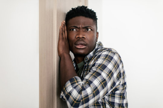 Curious Black Guy Listening Putting Ear To Door At Home