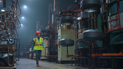 Focused woman supervisor walking at huge modern production facility warehouse.