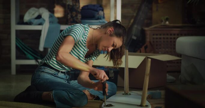 Cinematic shot of young creative woman is assembling wooden table to remodeling and renovation house by herself with diy techniques at home.