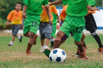 Obraz premium Football soccer children training class. Kindergarten school kids playing football in a field. Group of boys running and kicking soccer on sports grass pitch. Children in sportswear on football match.