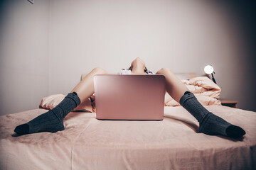 a young Asian webcam model girl is lying in front of a laptop with her legs spread. enjoys and shows her charms. low depth of focus,selective focus. - obrazy, fototapety, plakaty