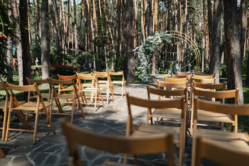 Wooden chairs at an outdoor pine forest wedding ceremony.