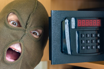 A cheerful man in a mask celebrates success by opening a safe on a numeric code