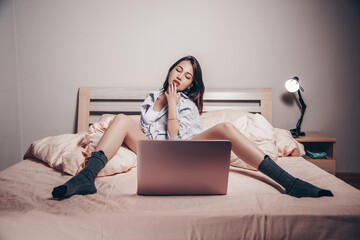 a young Asian webcam model girl is sitting in front of a laptop with her legs spread. she...