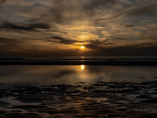 Zonsondergang bij laagwater aan het strand