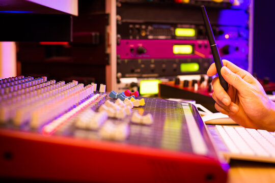 close up male sound engineer's hands as he concentrating on recording in front of audio mixing console