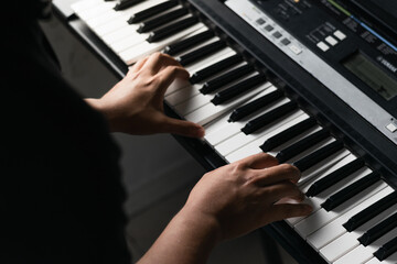 detail shot of a young latino boy's hands practicing and playing synthesizer, for his piano high...