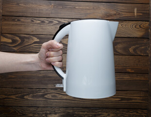girl holding an electric kettle on a wooden background.