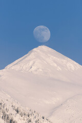 A cold winter day was coming to an end when the Moon started to creep up behind the mountain. Showing in full majestic glory. 
