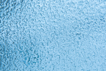 Abstract blue winter background. Texture of frozen water drops, ice surface on the window