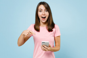 Young surprised amazed happy caucasian woman 20s wear pink t-shirt look camera hold in hand use...