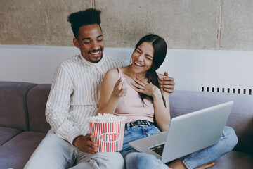 Two young friends laughing fun woman man of African American ethnicity in casual clothes watch...