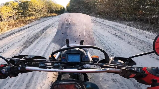 motorcyclist riding sandy off-road throw the forest. Driver's view from behind the wheel